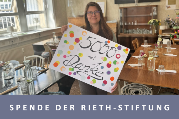 Eine Frau hält ein bunt gestaltetes Plakat mit der Aufschrift "5000 mal DANKE" in die Kamera.
